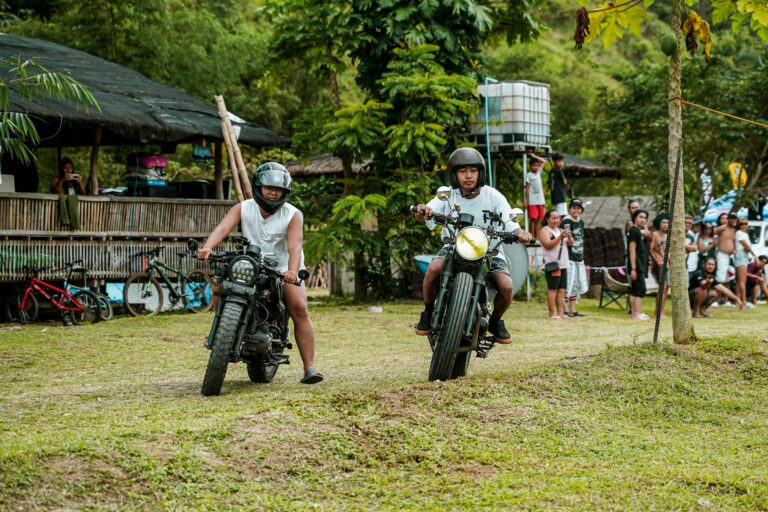 Two men on motorbikes in an outdoor event, surrounded by a lively crowd in Tanay, Philippines.